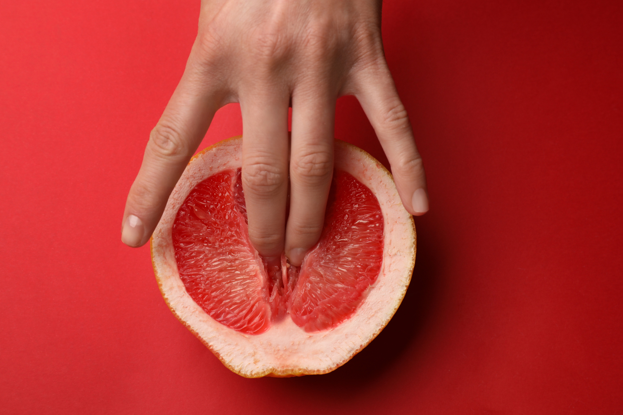 Woman Touching Half of Grapefruit on Red Background, Top View.  Concept